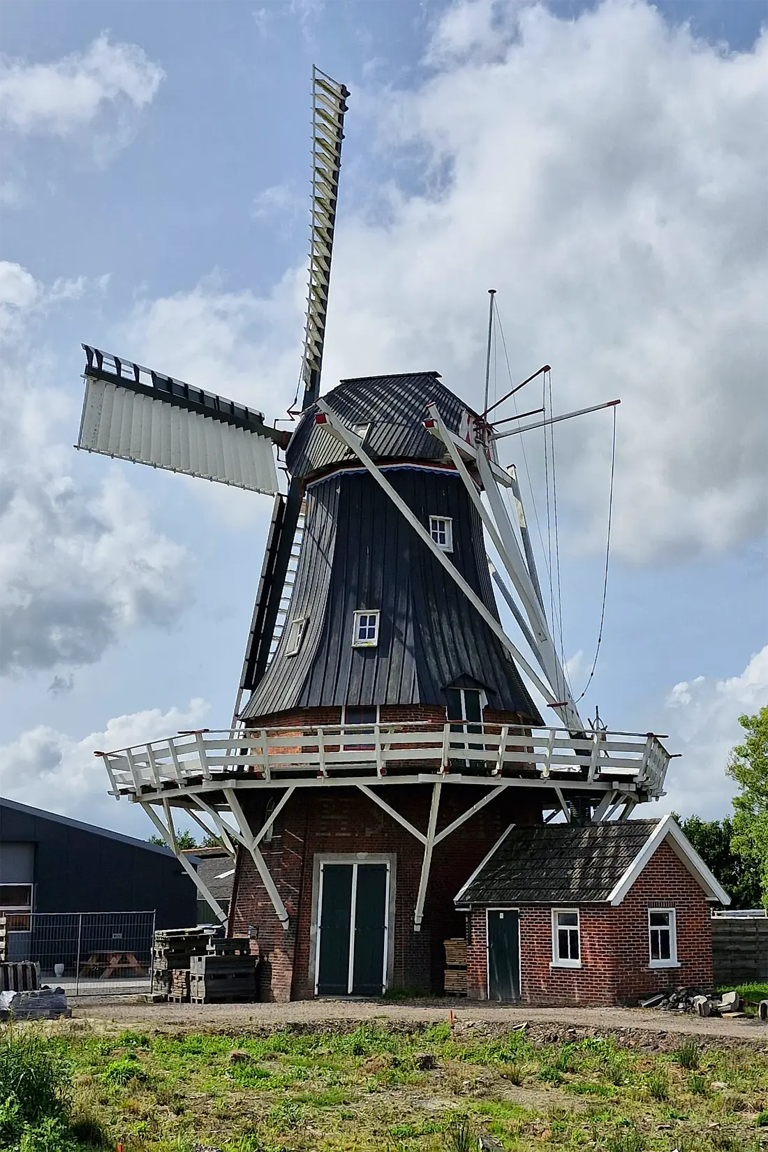 Molen 00622 Windlust (Overschild), Rob Hoving (23-10-2024)&nbsp;De molen met het motorhok, voor de aandrijving van een maalstoel in de molen. De beeldbepalende boerderij/molenaarswoning bij de molen is wegens aardbevingsschade helaas afgebroken. | Database Nederlandse molens