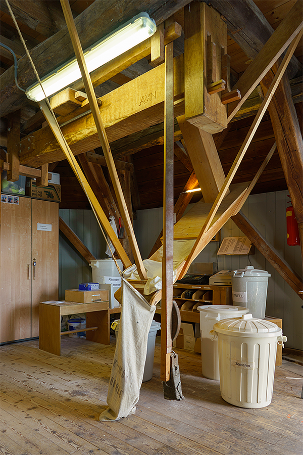 11, Molen 03123 Benninkmolen (Doetinchem), Marcel van Nies (17-4-2018). Er worden met één trommel kleine hoeveelheden gemalen, voor eigen winkel en voor de wereldwinkel in Doetinchem. Kunststof bakken zijn daarvoor het adekwaatst, maar als het moet kan het meel ook in zakken zakken. | Database Nederlandse molens