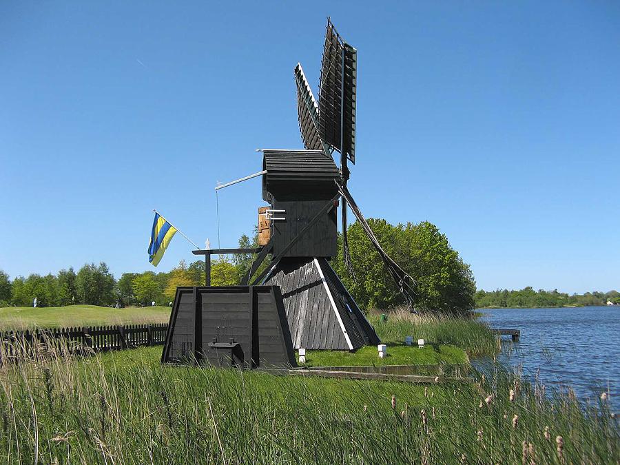 7, Molen 12591 De Himriksmole of De Groene Ster (Tietjerk / Tytsjerk), Met de Leeuwarder vlag op de staart. Rechts het water van de Kleine Wielen.  Jacob Bijlstra (2-6-2013). | Database Nederlandse molens