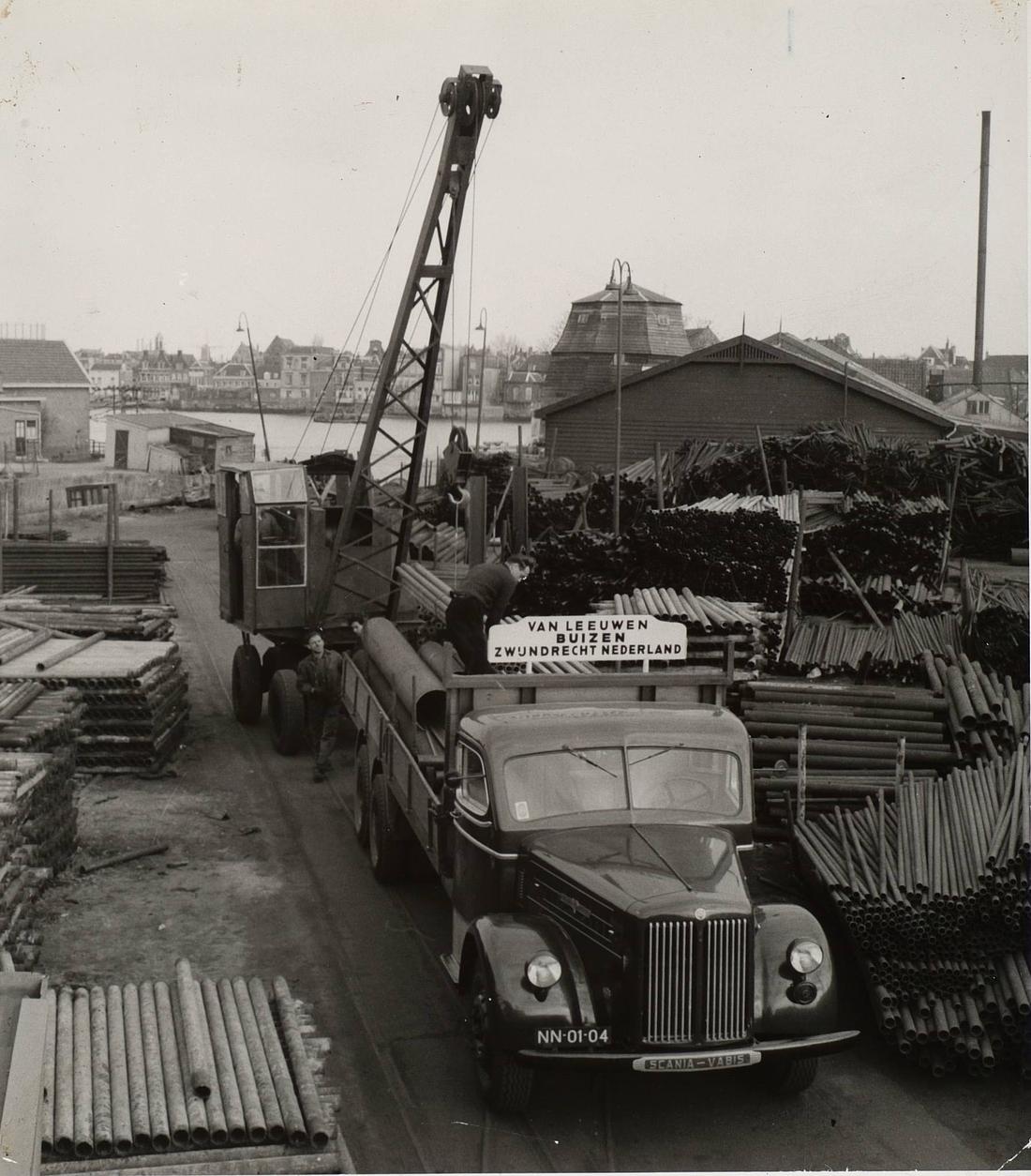 8, Molen 01270 Welgelegen / Dikke Molen (Zwijndrecht), Arbeiders aan het werk bij Van Leeuwen Buizen op het industrieterrein Oostkeetshaven langs de Oude Maas in Zwijndrecht, Ringdijk 188 indertijd. De afgeknotte molenromp is de molen Welgelegen. collectie RAD | Database Nederlandse molens