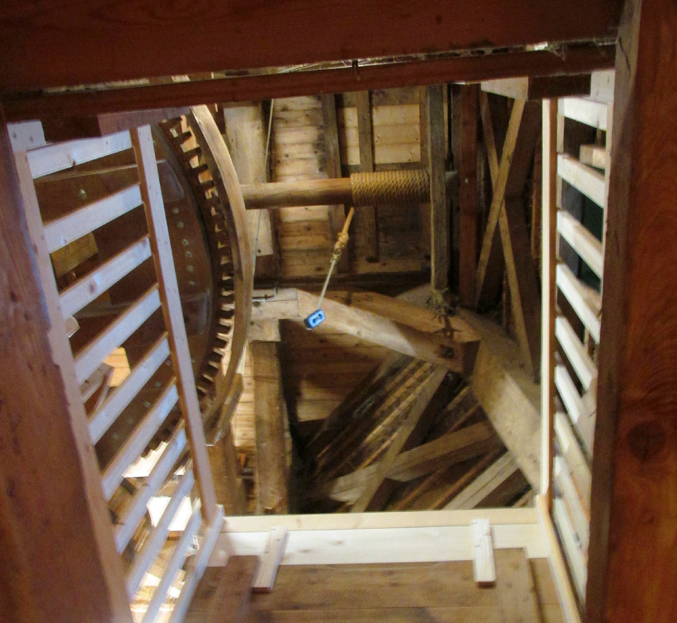 15, Molen 01639 De Traanroeier (Oudeschild), Piet Glasbergen (27-1-2018)Ongebruikt trapgat naar steenzolder. geeft doorkijk naar luiwerk en spoorwiel, dat aan die kant een gebogen lat om de kammen heeft. | Database Nederlandse molens