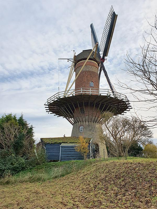 7, Molen 03540 De Hoop (Wolphaartsdijk), Pieter Zuijkerbuijk (1-12-2019)Aan de achterzijde van de molen bevindt zich de zijingang naar de werkplaats en het motorhok. | Database Nederlandse molens