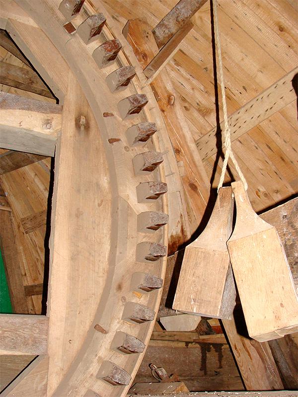 14, Molen 03601 Zwinnemolen (Zuidzande), Jan de Witte (8-8-2012)De houten hoepelvang 4Achter de twee houten pal gewichten ziet men rechts de boven het voeghout gelegen vangbalk. Hier doorheen zit de vangplank (nog net zichtbaar). | Database Nederlandse molens