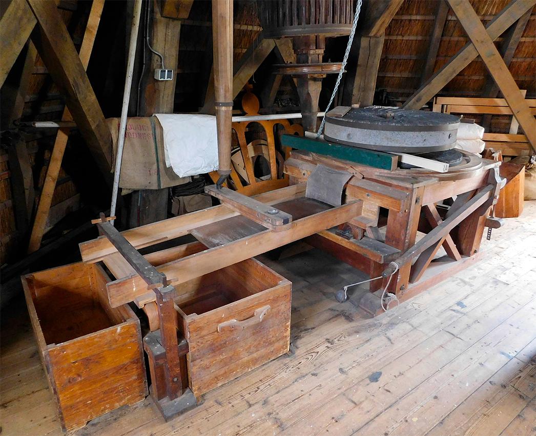 18, Molen 10673 De Ster (Rotterdam), Piet Glasbergen (27-6-2018)Schudzeef; beide koppels hebben er één. De zeef wordt aangedreven door een vertikale as, de band die de as laat draaien komt van de as van het steenrondsel. De band kan strakgetrokken worden met een schuif. Eea is goed te zien op het plaatje van William. Onderaan de zeef-as zit een krukasje, dat bewerkstelligt de heen-en-weer-beweging. De zeefbak loopt op rolletjes.  | Database Nederlandse molens