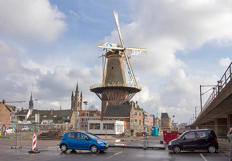 1, Molen 03503 De Roos (Delft), De Roos draaiend met 'Delft-blauwe' zeilen, nog voorlopig in een chaotische omgeving. Het spoorviaduct rechts is nu buiten gebruik en zal worden gesloopt.  Willem Sterenberg (21-2-2015). | Database Nederlandse molens