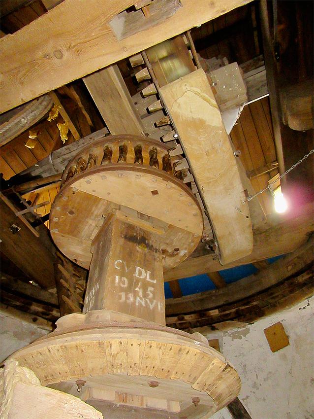 17, Molen 01904 Zeezicht (Nieuwenhoorn), Frank Moerland (14-8-2019)De koningspil met diverse initialen, onder het conische wiel voor de aandrijving van het luiwerk. | Database Nederlandse molens