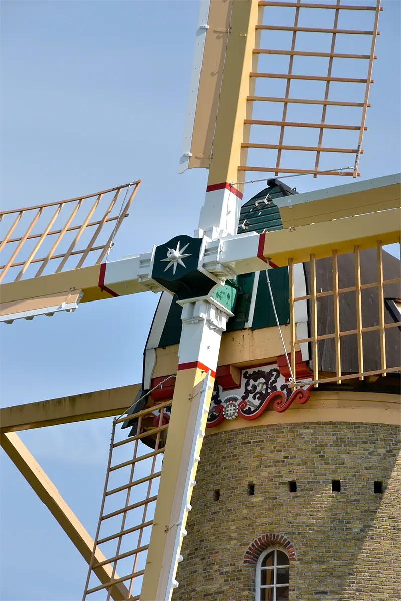 5, Molen 10336 De Speelman (Rotterdam), Rob Pols (18-5-2023)De Speelman met zijn nieuwe wiekenkruis. De kleuren van de roeden en het houtwerk zijn zoals op de oorspronkelijke standplaats aan de Delftweg in Overschie voor het grootste deel geel. De vergrendeling van de windborden is toegepast met wervels en borgscharnieren. De windborden zelf zijn een flink stuk breder dan die van het oude wiekenkruis. Ook zijn na decennia van afwezigheid de zeilrails in ere hersteld.  | Database Nederlandse molens